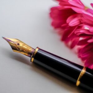 black and gold-colored fountain pen beside flower